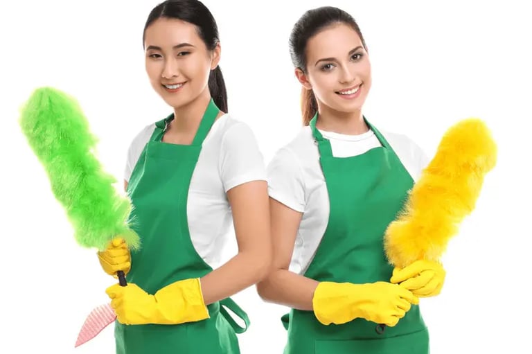 two women in green aprons holding cleaning supplies