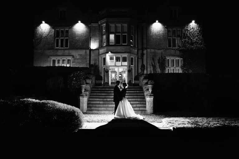 a bride and groom standing in front of a large mansion