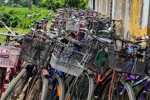 Around 200 bikes leaning against school building.