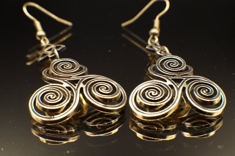 a pair of brass triskelion earrings with triquetra accents, custom cut out of 1.64mm brass