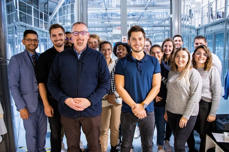 A diverse group of smiling professional office colleagues posing for a team photo in a modern workplace.