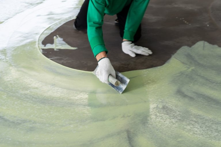 a person in a green shirt is applying an epoxy in a concrete floor