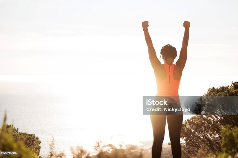 a woman standing on a hill with her arms up in the air