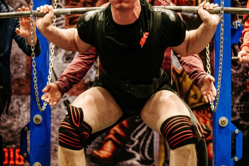 a man in a black shirt and knee pads on a bench