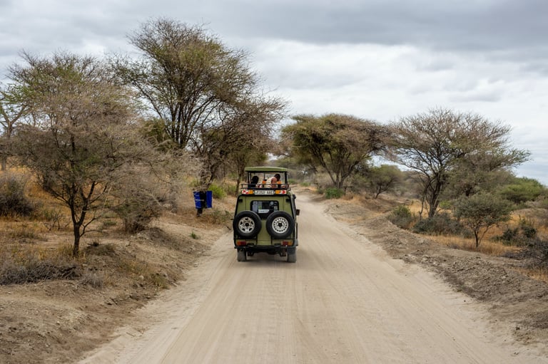 a jeep driving down a dirt road with people in the background