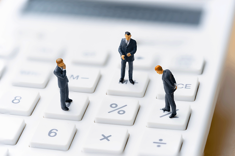 miniature people standing on top of a calculator