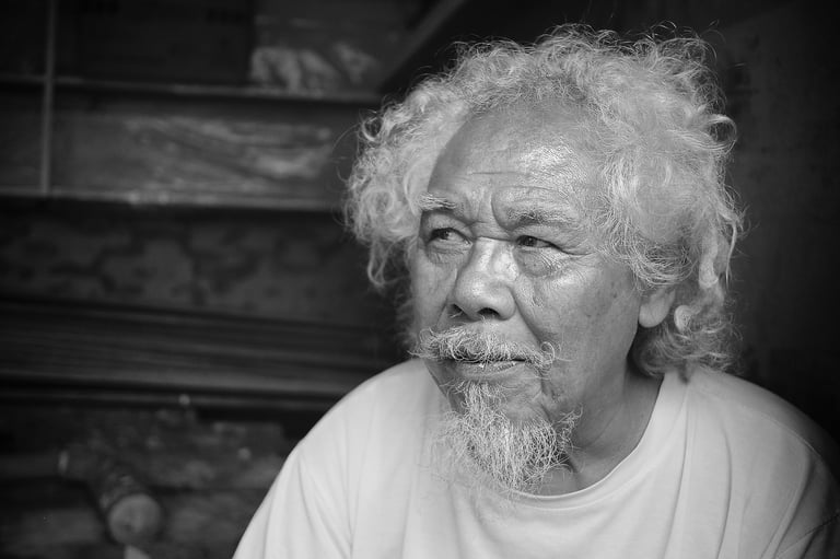 A portrait of an older Indonesian man with white hair and beard by Peter Pickering