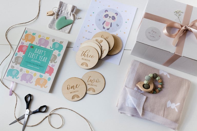 A flat lay with a toy, green stone, book, blanket and wooden age discs.