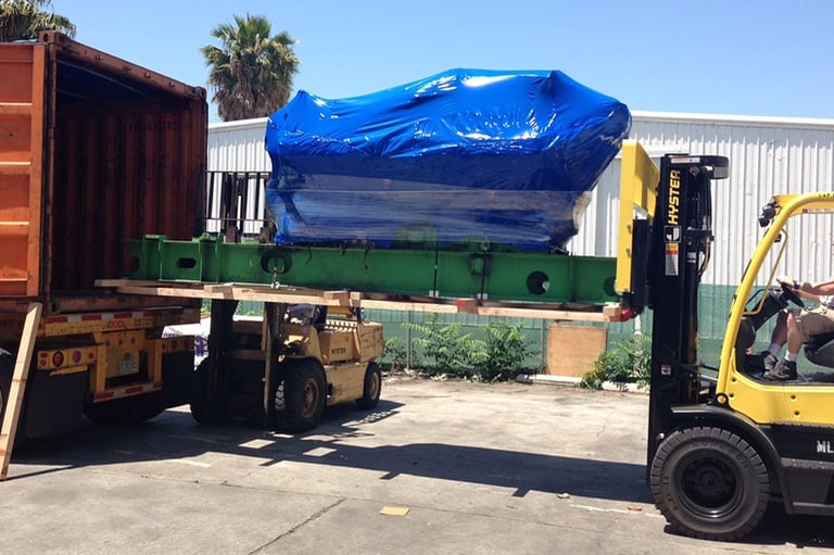 loading a large item with a large blue tarp into a truck
