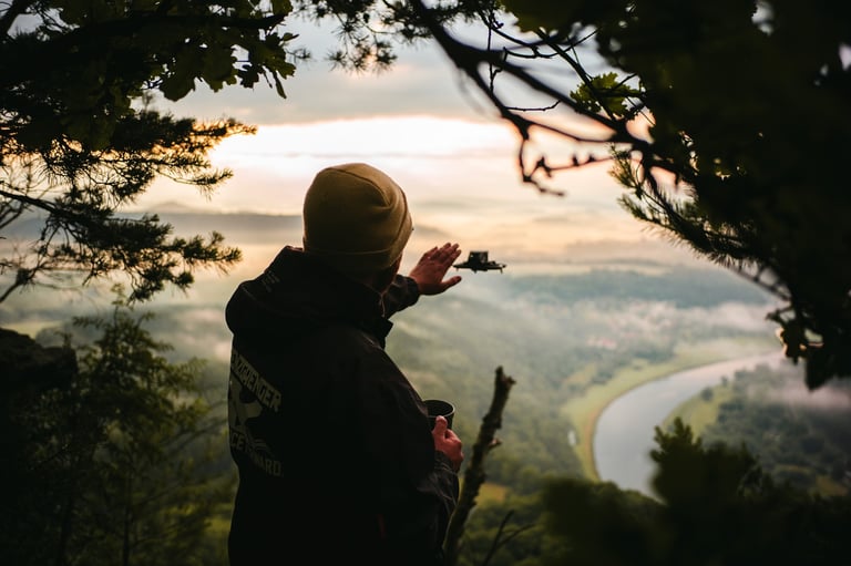 a person standing on a mountain top with a dji drone in the air