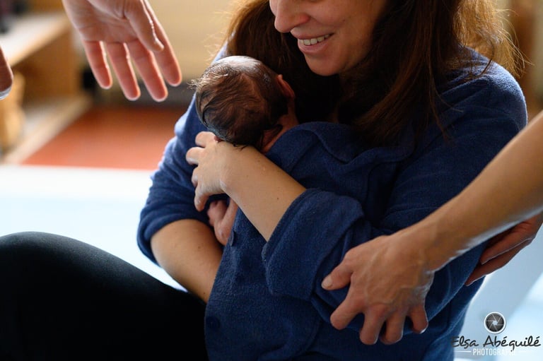 Une maman tenant son nouveau-né dans les bras après le Bain des Merveilles
