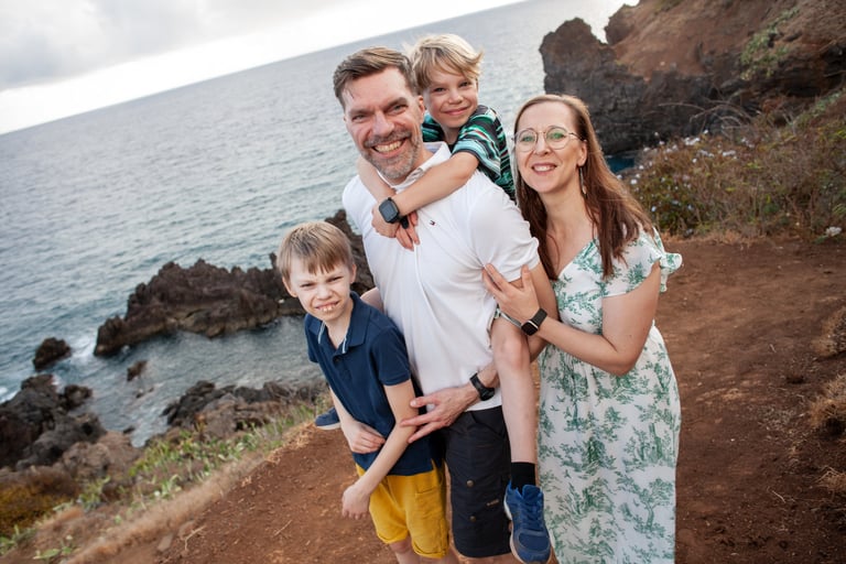 Family portrait on rocks at Lido Promenade Madeira with ocean cliffs by Mihail Zhelezniak