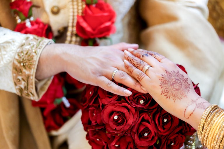 pakistani bride and grooms hands wearing wedding rings against the bride's bouquet as the backdrop 