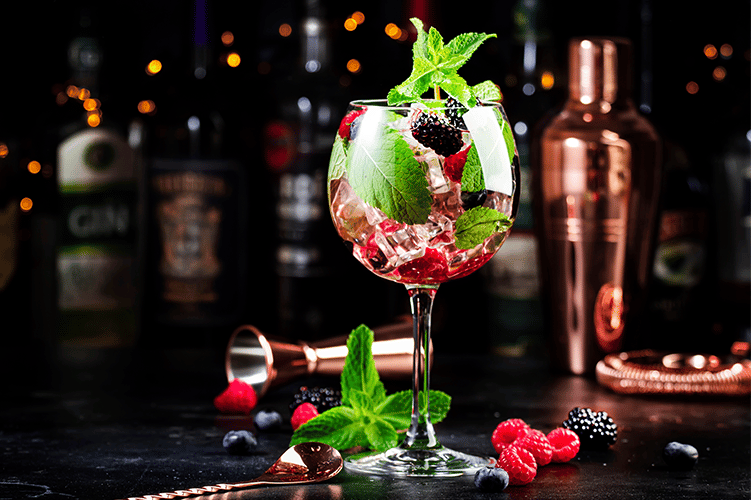 a glass of wine with berries and mint leaves de Lu Mezcal