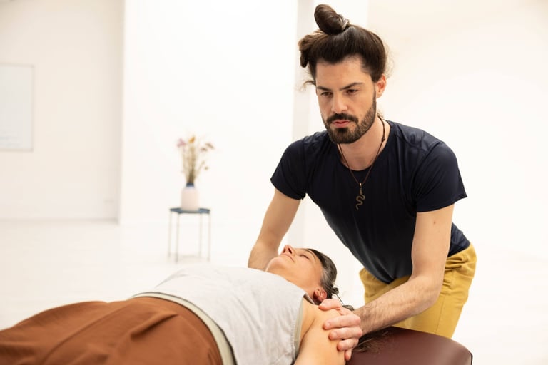 practitioner touching arms of client focused intently on client laying on a massage table