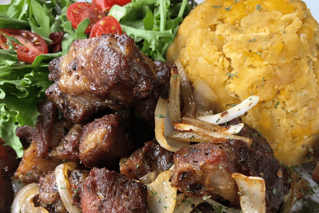 a plate of carne frita con mofongo and vegetables