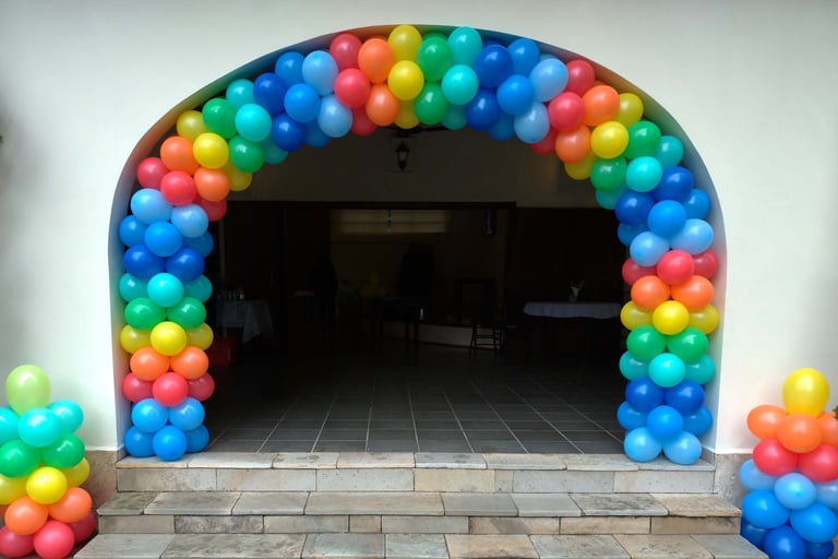 Arco de balões colorido na entrada de aniversário, criando ambiente alegre e acolhedor.
