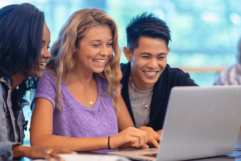 imagem de três jovens reunidos olhando para um computador estudando sobre finanças.