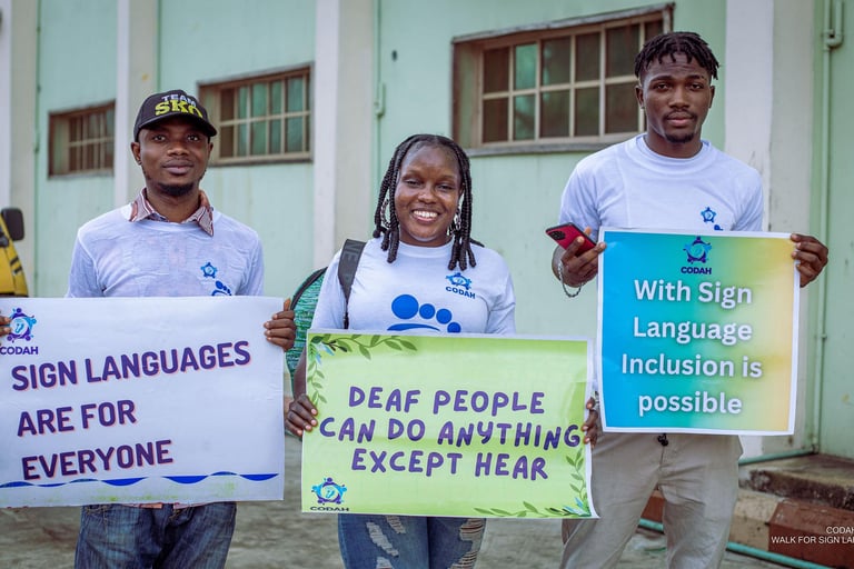 2 males and females holding a placard in recognition of sign language use and Deaf people.