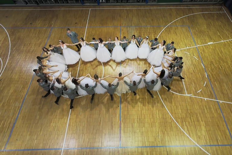 beltéri FPV drónos kép egy sportcsarnokban rendezett szalagavató bálról ahol ovális formában táncol