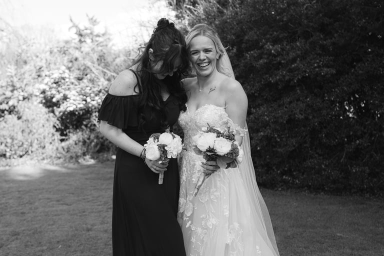 bridesmaid and bride laughing with each other holding bouquet