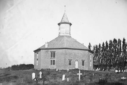 An octagonal church building with a graveyard in black and white