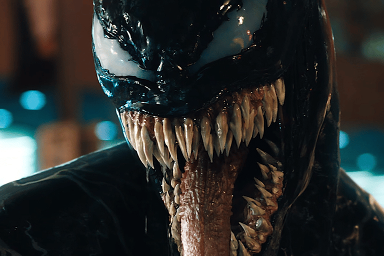a man in a black suit and a mask with a mouth open
