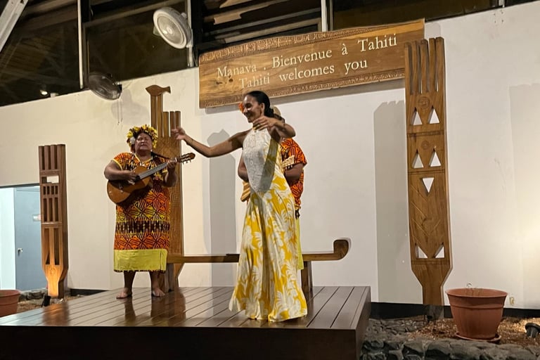 Tahitian dancers and musicians performing a welcome ceremony below a 'Tahiti welcomes you' sign