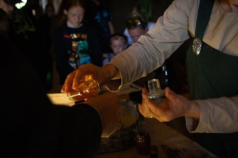 a person is holding a glass bottle places a drop of tincture onto the back of another person's hand