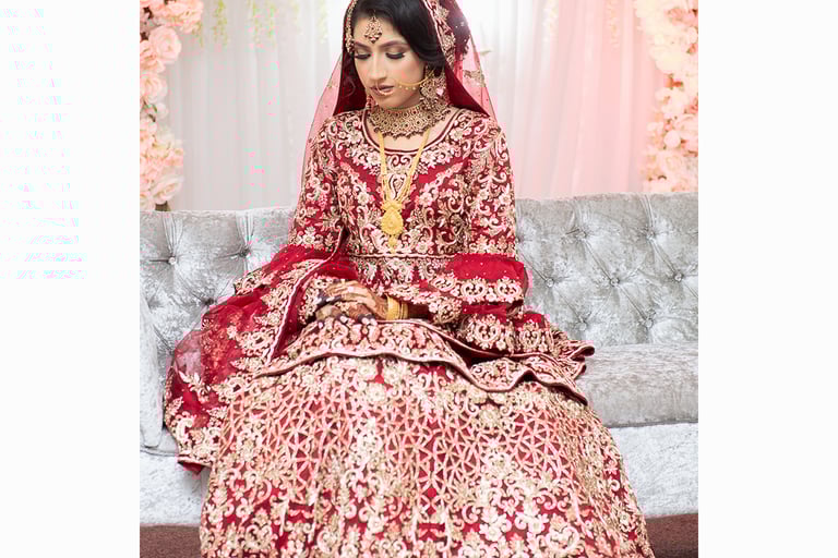 photo of asian bride in red traditional dress with gold embroidery wearing traditional asian gold jewellery 
