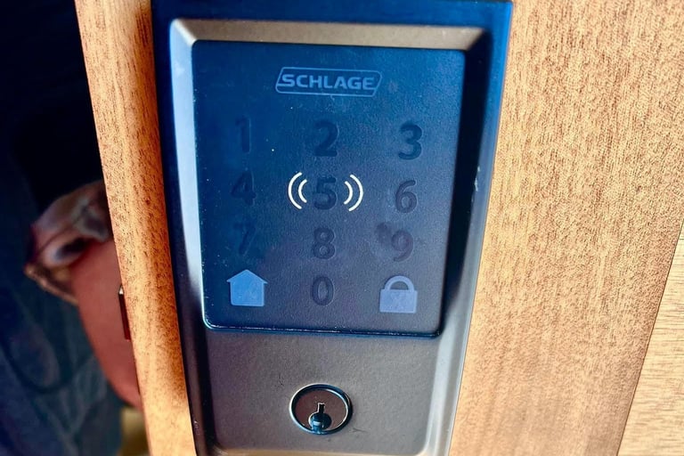 A close up of a wooden door with hand touching a smart lock, representing Jack’s Locksmith local smart locks services