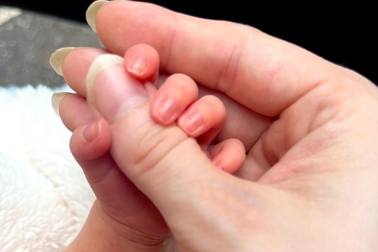 Newborn baby holding mothers thumb for the first time, symbolizing early motherhood bond and emotional connection