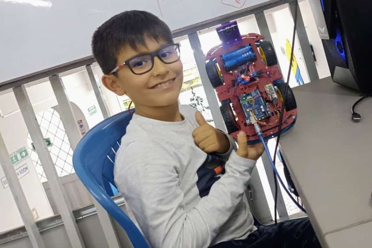 a boy sitting at a desk with a computer mouse