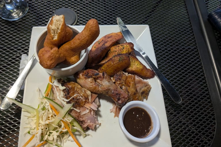 a plate of jerk chicken, plantains and festivals