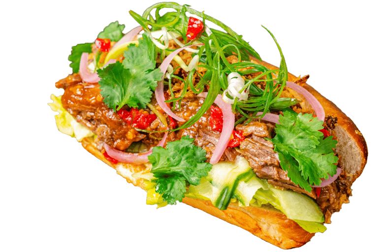 a sandwich with juicy pulled beef, red chillies, coriander, spring onions and pickled onions