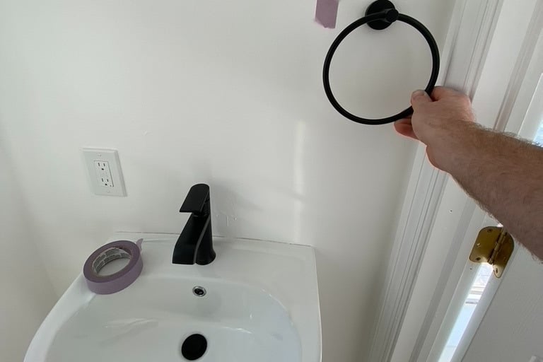 Hanging towel right over pedestal sink in bathroom performing handyman tasks