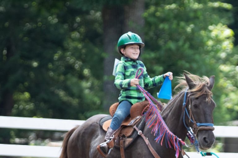 a junior riding a horse in a fenced in area