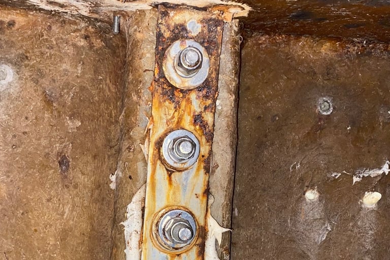 Damaged stainless steel chainplate on the back of a cruising sailboat