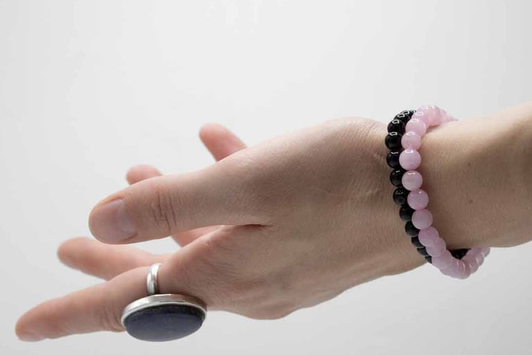a person's hand holding a rock with a beaded bracelet