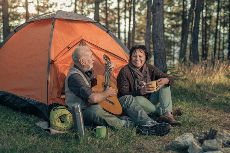 Older man and woman camping and playing guitar free from urinary incontinence worries