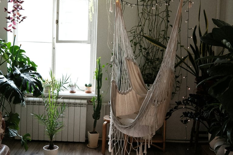 Fauteuil suspendu style bohème devant une fenêtre, nombreuses plantes