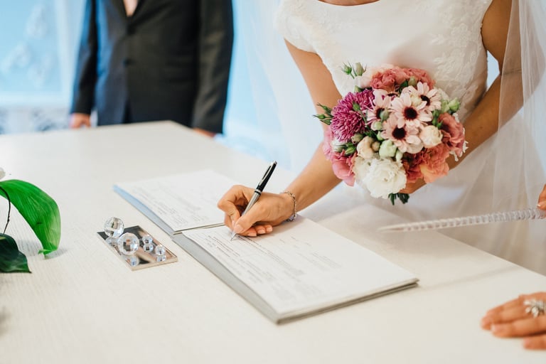 Bride signing the wedding register with bouquet—enquire to book your Glasgow wedding videographer.