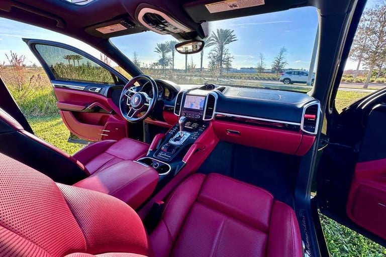 Interior of a luxury SUV with red leather seats and black trim, freshly detailed and parked under clear Florida skies
