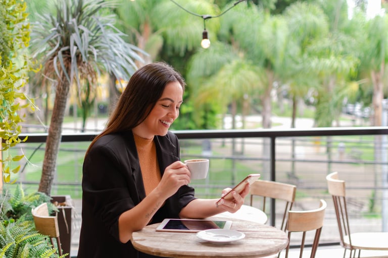 uma mulher sentada a uma mesa com uma xícara de café