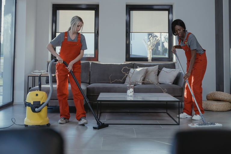 two people in red overalls cleaning a living room
