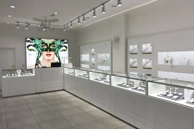 Modern white jewelry store interior with luxury glass display cases and bright track lighting.