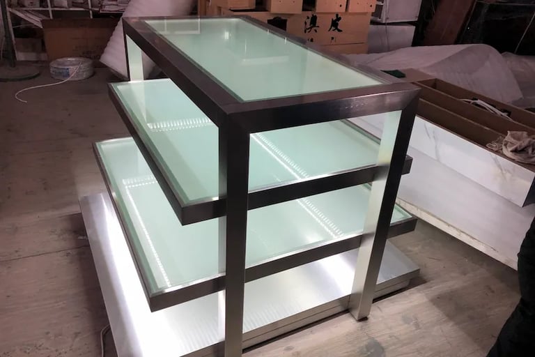 Modern 3-tier stainless steel display stand with illuminated frosted glass shelves for retail stores.