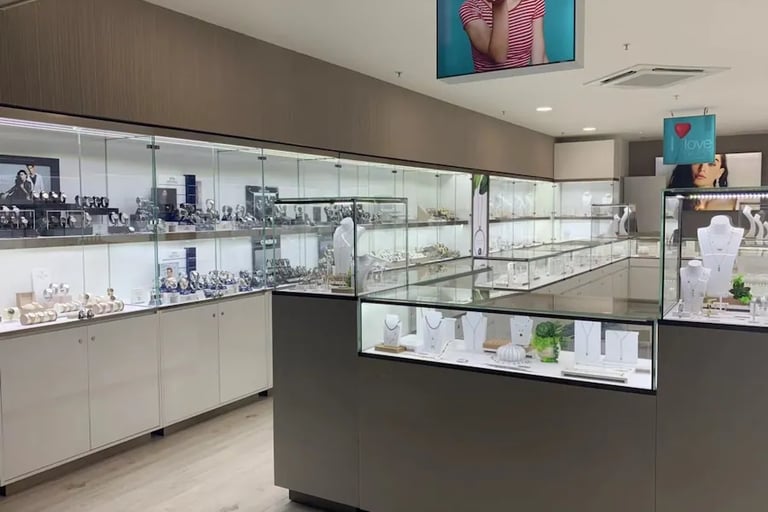 Jewelry store interior with luxury watches and necklaces displayed in glass cases.