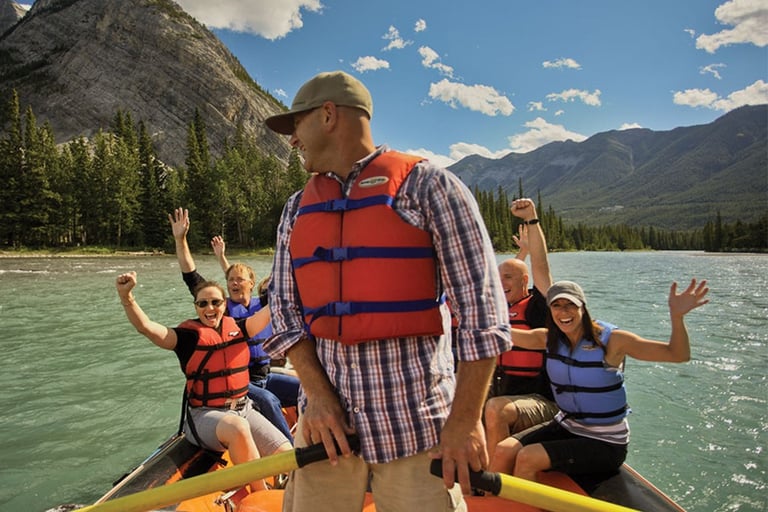 A happy group white water rafting on a mountain river wearing life jackets.