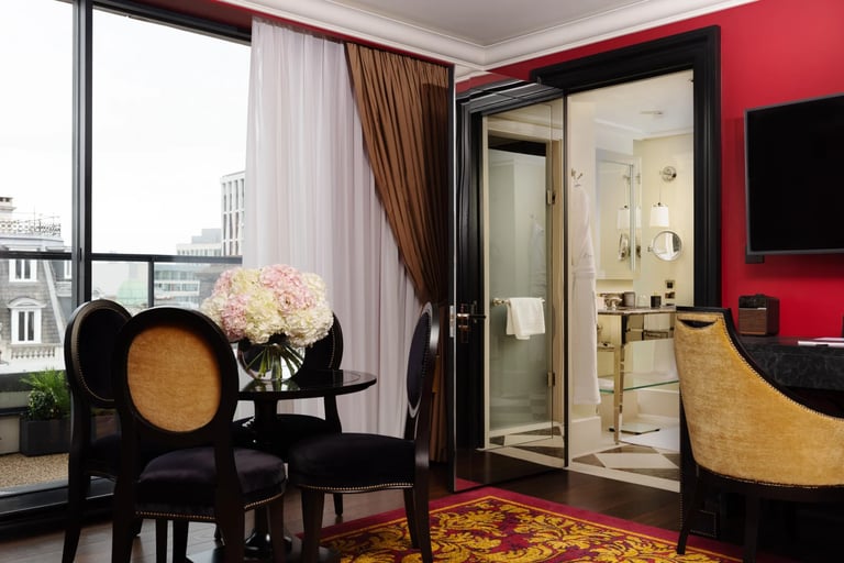 Luxury hotel suite interior featuring elegant furniture, a dining area, and a view of the city skyline.